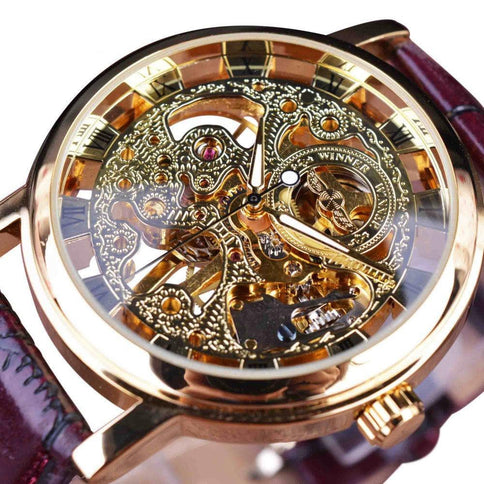 Intricate gold automatic watch for men with a transparent skeleton dial showcasing detailed mechanical workings and a brown leather strap.