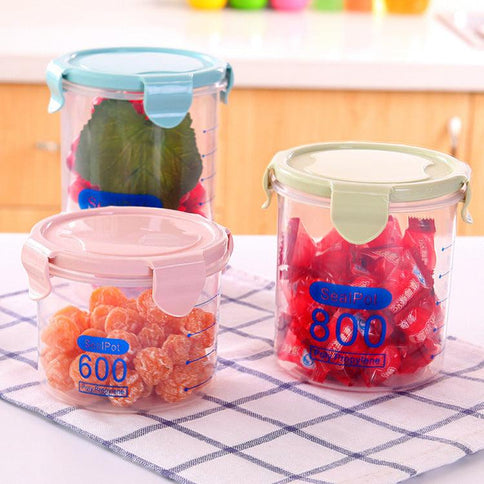 Three transparent sealed plastic food storage containers featuring colorful lids, perfect for organizing fruits and snacks in the kitchen