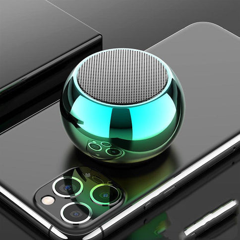 Portable Bluetooth speaker in a sleek spherical design, featuring a shiny green finish, placed on a smartphone