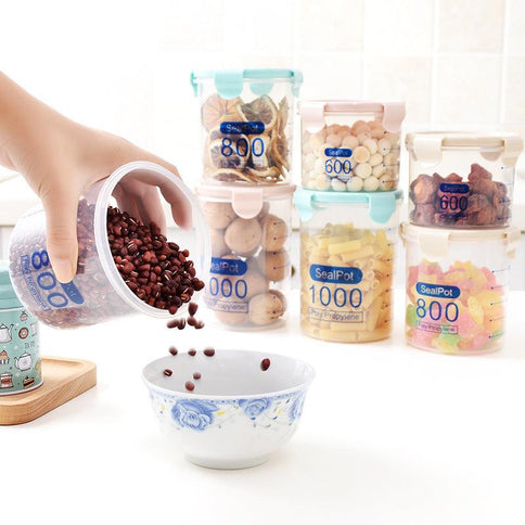 Hand pouring beans from a transparent sealed plastic food storage container into a bowl, surrounded by more containers