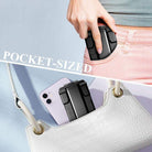 Pocket-sized adjustable cell phone stand in black being inserted into a handbag for convenient carrying and easy use