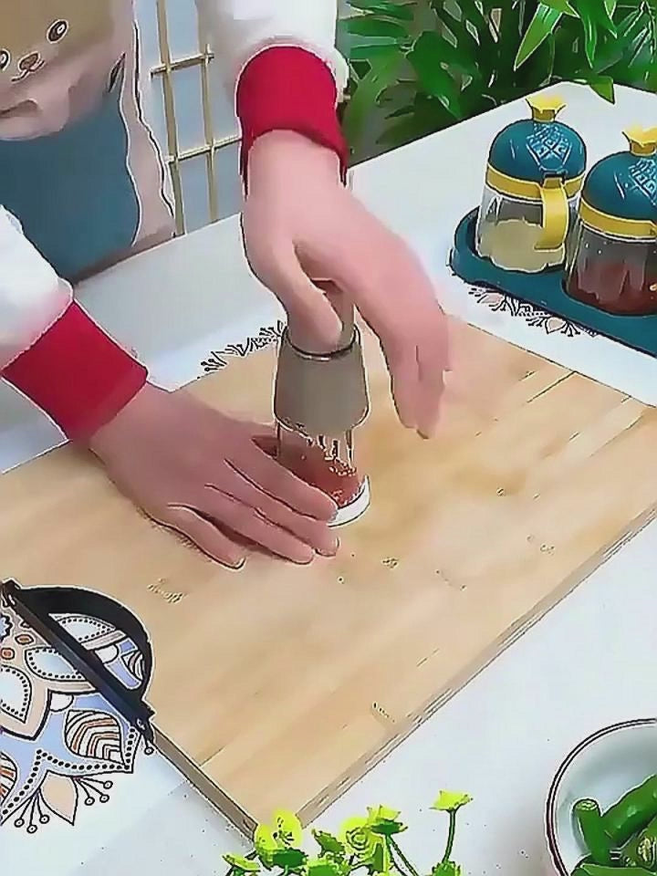 Hands using a vegetable chopper and garlic press on a wooden cutting board to prepare ingredients for cooking