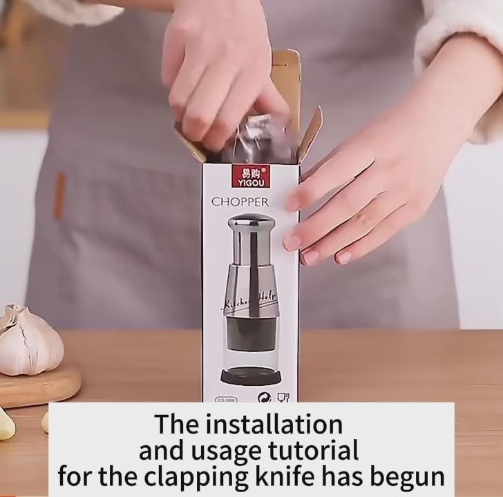 A person unboxing a vegetable chopper and garlic press, showcasing the sleek design and instruction manual in a kitchen setting